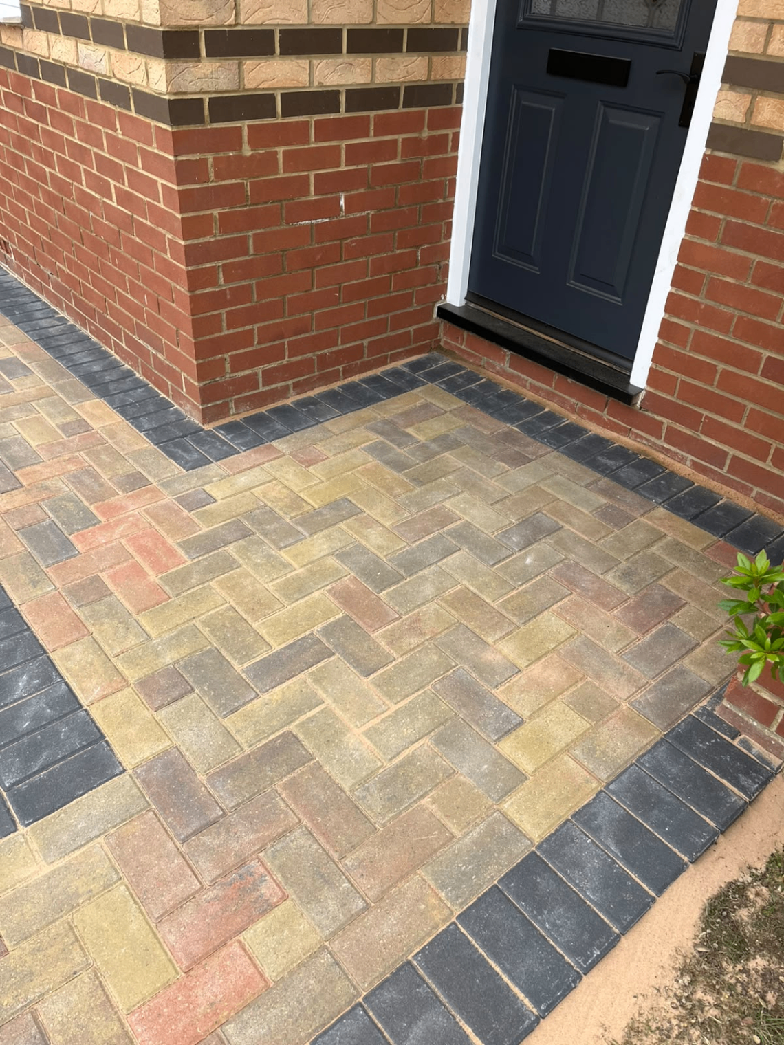 Close-up of block paving and charcoal border by a front door